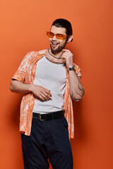 Handsome Caucasian man wearing trendy white t-shirt and orange cardigan.