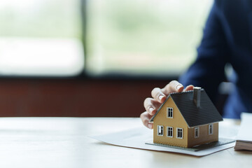 Close up real estate agent holding small house model, Home loan.