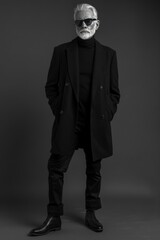 Elderly man modeling a sleek, monochrome outfit, with a sharp haircut to match the contemporary studio setting