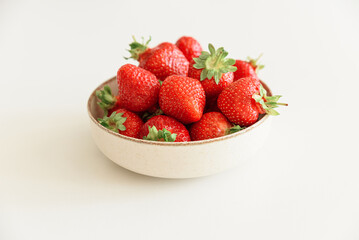Fresh strawberries into bowls on white table. Summer food concept. Soft focus