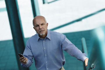 Fototapeta premium Senior businessman using smartphone app walking up stairs