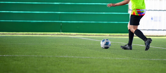 Soccer players in action during a game on a grass field, focusing on their legs and the ball.