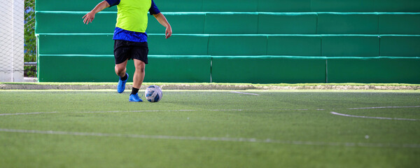 Soccer players in action during a game on a grass field, focusing on their legs and the ball.