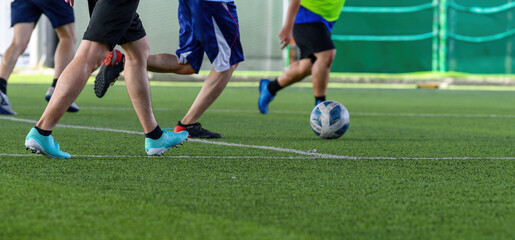 Soccer players in action during a game on a grass field, focusing on their legs and the ball.