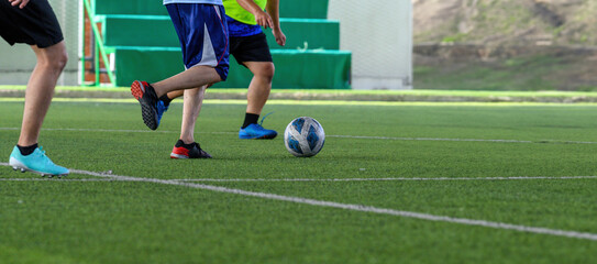 Soccer players in action during a game on a grass field, focusing on their legs and the ball.