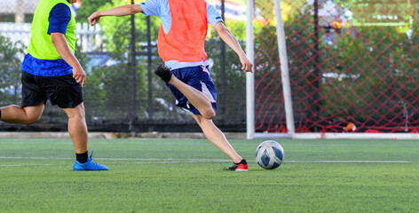 Soccer players in action during a game on a grass field, focusing on their legs and the ball.