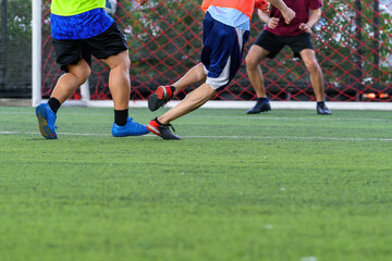 Soccer players in action during a game on a grass field, focusing on their legs and the ball.