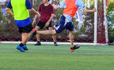 Obraz premium Soccer players in action during a game on a grass field, focusing on their legs and the ball.