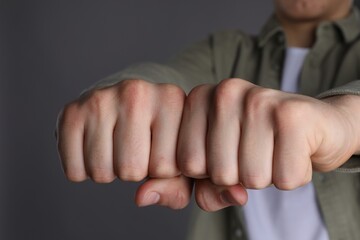 Obraz premium Man showing fists with space for tattoo on grey background, closeup