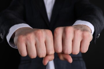 Obraz premium Businessman showing fists with space for tattoo on black background, closeup