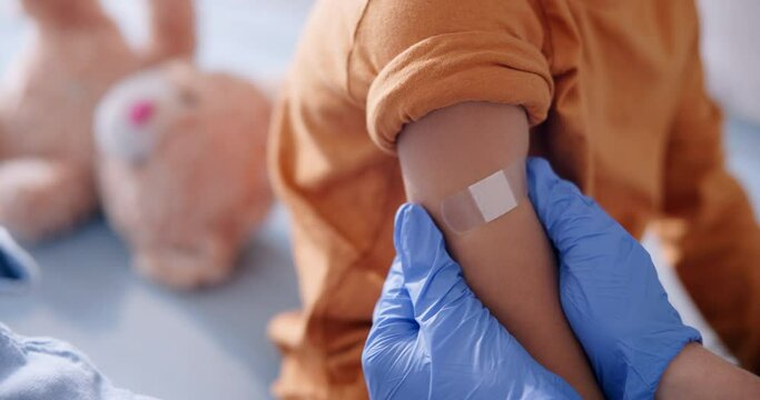 Child, arm and pediatrician hand with bandage for immunization shot or assessment, healthcare or checkup. Kid, clinic and helping consultation with medical vaccine or youth job, diagnosis or plaster