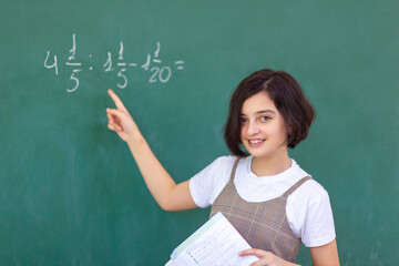 Beautiful girl at the blackboard solves a math problem