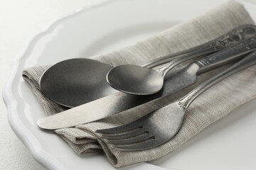 Stylish setting with cutlery, napkin and plate on table, closeup