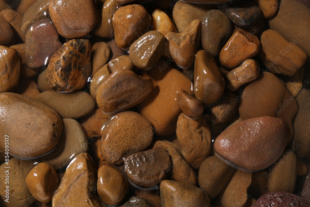 Wall mural Beautiful pebbles in water as background, top view