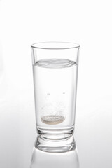 Effervescent pill dissolving in glass of water isolated on white