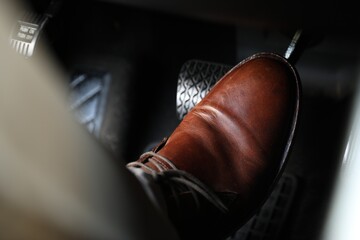 Man pushing on pedal of car brake, closeup