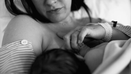 Monochrome moment of new mother breastfeeding her newborn baby after childbirth in black and white...