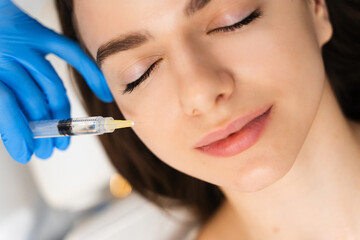 Cosmetology injections for getting rid of wrinkles. Young caucasian girl improves skin condition in cosmetology clinic.