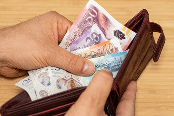 Hand takes out money from the wallet, British Pound banknotes, concept, rising prices, value of...