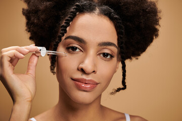 Obraz premium A young African American woman applies serum to her face with a dropper.