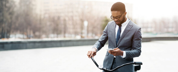 Black businessman on a bicycle is in the city, checking his smartphone. The scene is energetic and contemporary, highlighting a seamless blend of work and transportation in an urban setting.