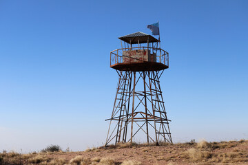 
Control lookout tower on the top of a mountain. Old metal tower with graffiti and flag to observe and control.