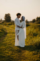 newlywed couple in love in a field in nature at sunset in summer