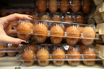 A person is reaching for a carton of eggs