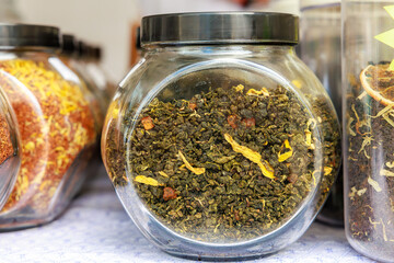A jar of green tea is sitting on a table next to other jars