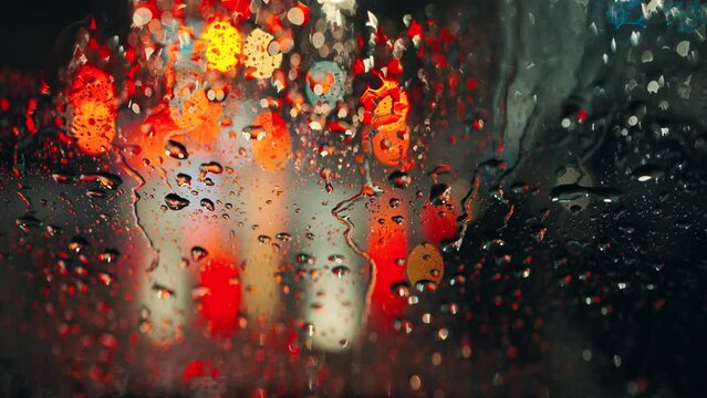 Lights of the evening city and passing cars through a wet rainy window.