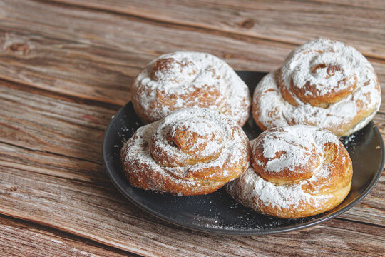 Several Ensaimada on a plate, on a brown table, typical Spanish sweet from the Balearic Islands