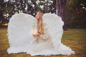 Girl angel with a candle in the evening forest