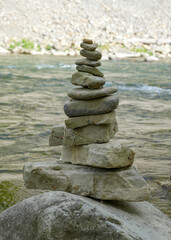 Stones arranged in zen towers by the river bed, balanced stones, pebbles stacks in a river, stone pyramid in the river in the mountains