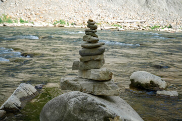 Stones arranged in zen towers by the river bed, balanced stones, pebbles stacks in a river, stone pyramid in the river in the mountains