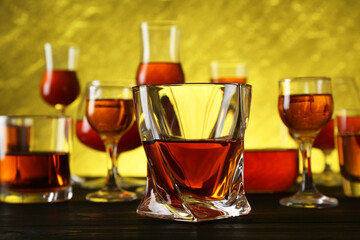 Different delicious liqueurs in glasses on dark wooden table