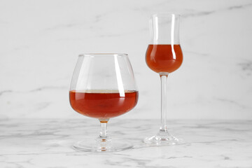 Delicious liqueurs in glasses on white marble table