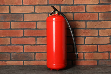 One red fire extinguisher near brick wall