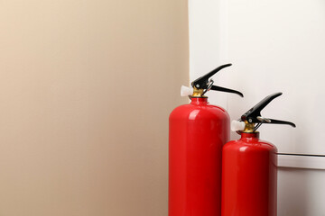 Obraz premium Two fire extinguishers near beige wall indoors, space for text