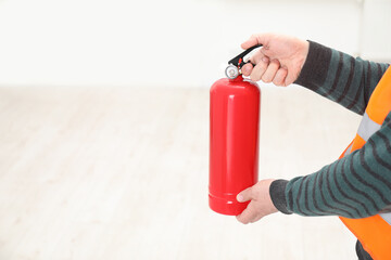 Naklejka premium Man with fire extinguisher indoors, closeup. Space for text