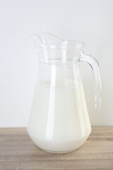 Jug of fresh milk on wooden table