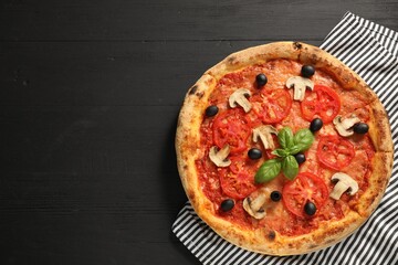 Delicious pizza with tomatoes, mushrooms, olives and basil on black wooden table, top view. Space for text