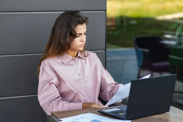 Businesswoman working on laptop outdoors in cafe