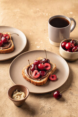 Breakfast toast with chocolate paste, sweet cherry and almond petals on beige textured background. Breakfast for kids