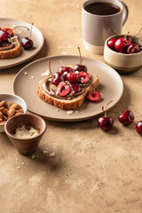 Breakfast toast with chocolate paste, sweet cherry and almond petals on beige textured background, text space