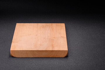 Empty wooden cutting board on dark textured concrete background