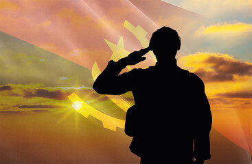 Silhouette of a soldier with a background of the Angola flag and a sunset or sunrise. Concept of national holidays. Commemoration Day.