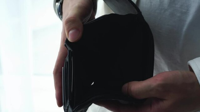 An empty wallet in the hands of a man.
There is no money in the wallet.
Man without money