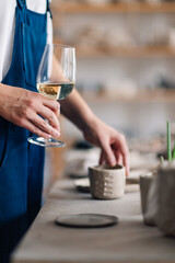 Close up of craftswoman's hand holding wineglass at pottery workshop.