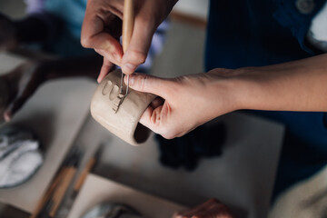 Close up of pottery class tutor showing decorating techniques to attendees