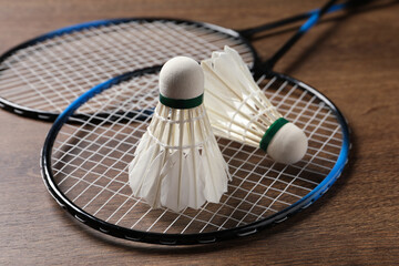 Feather badminton shuttlecocks and rackets on wooden table, closeup